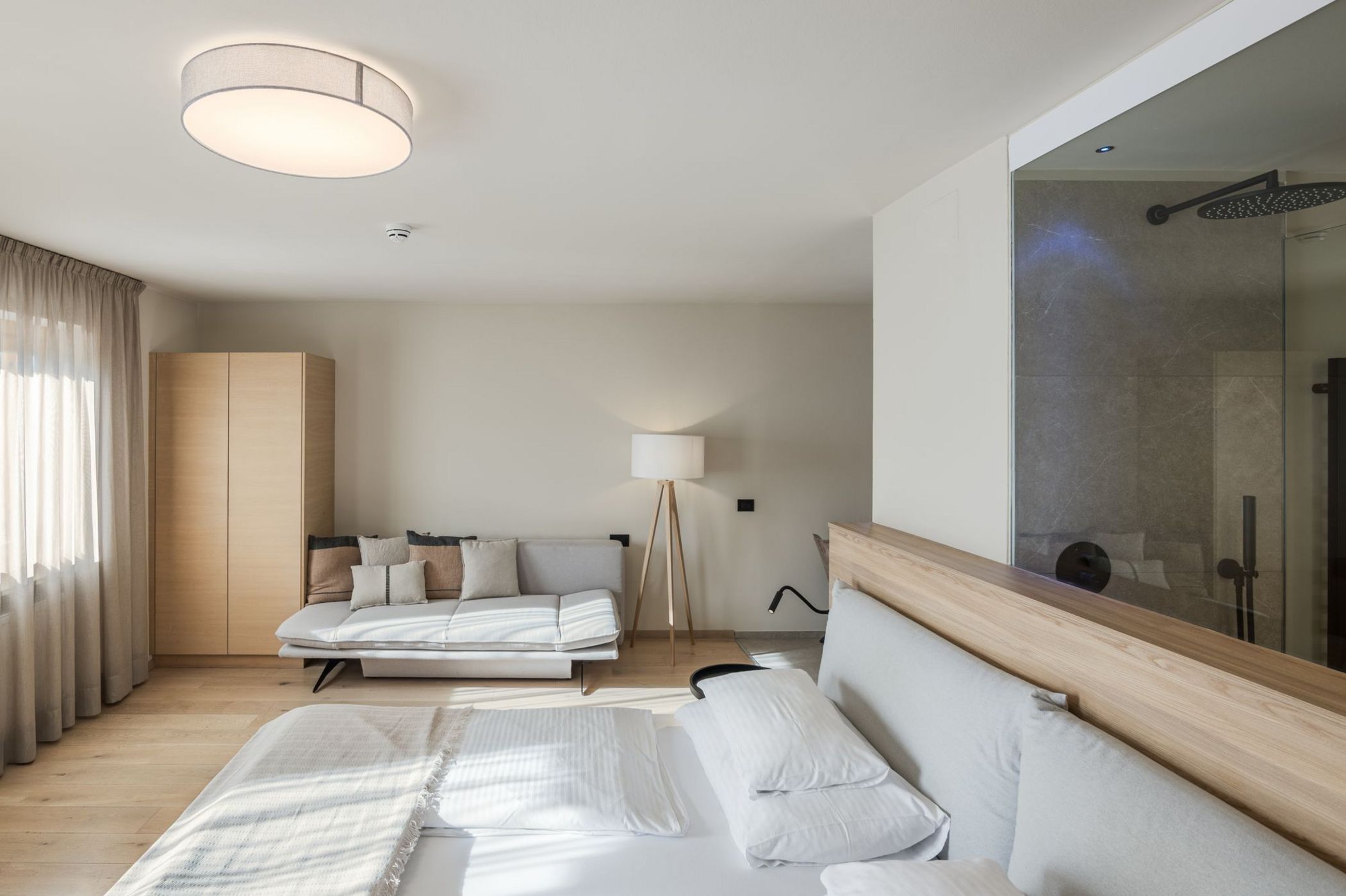 Camera da letto moderna con letto, divano, armadio e bagno con doccia a vista.