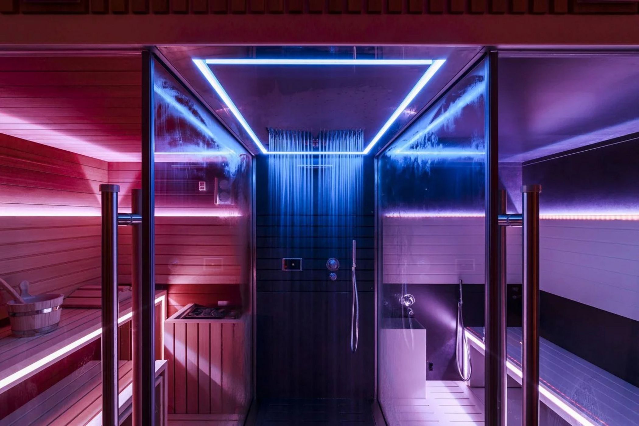 Doccia moderna con luci LED blu all'interno di una sauna in legno.