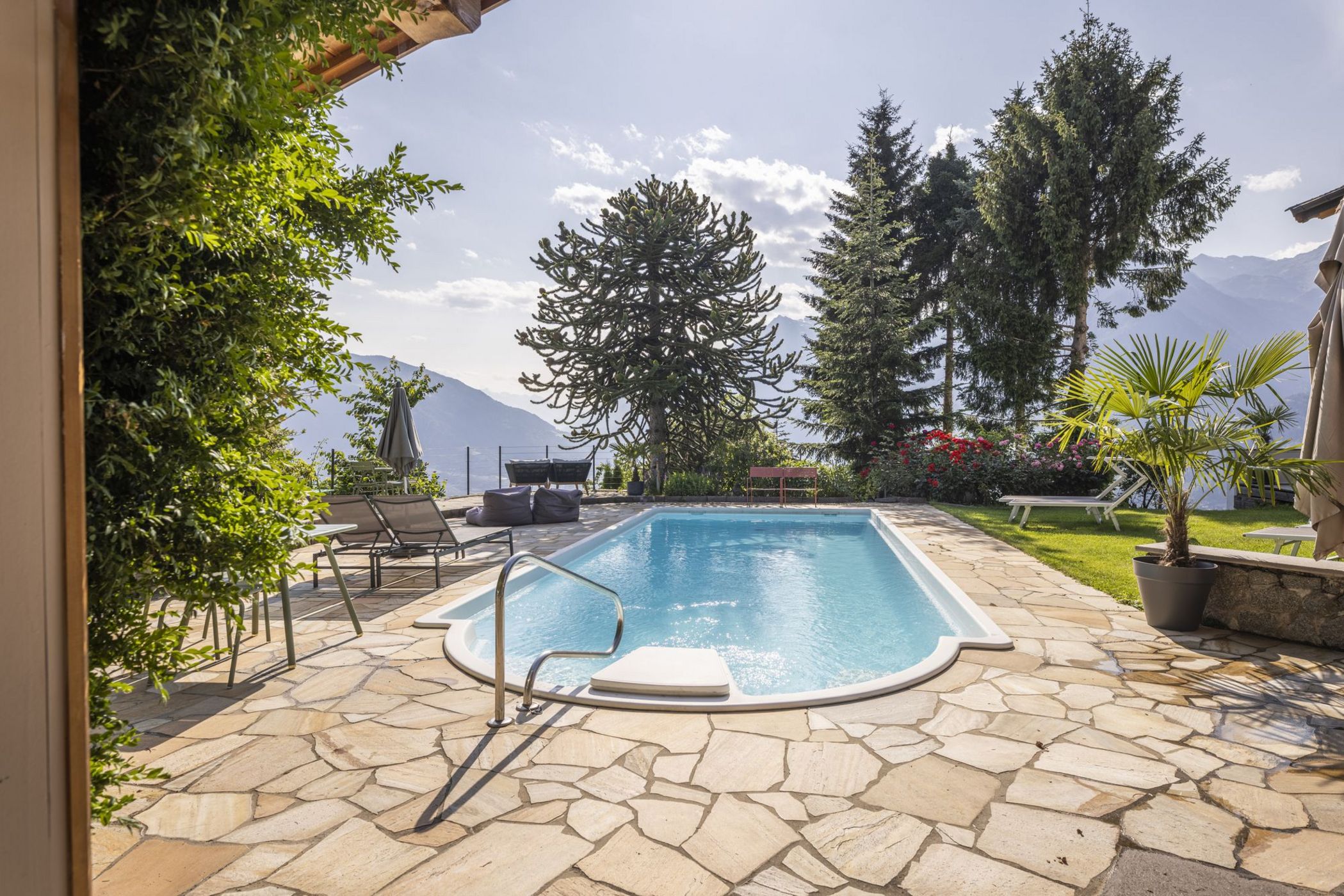 Piscina all'aperto con area solarium e vista montagna