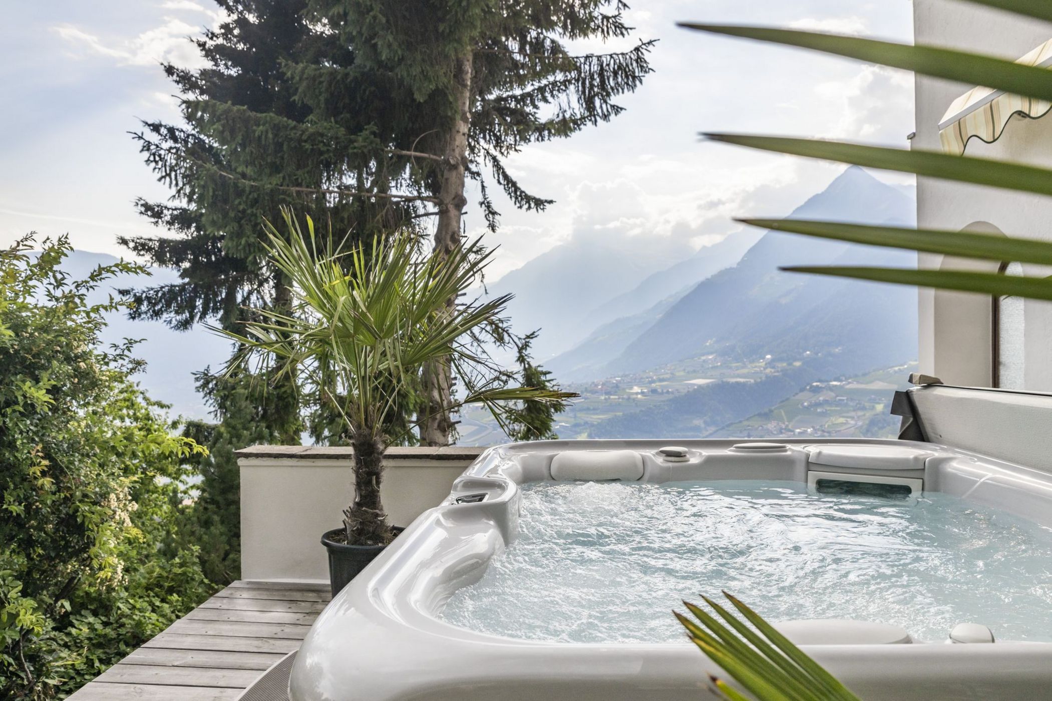 Vasca idromassaggio all'aperto con vista sulle montagne e piante verdi.